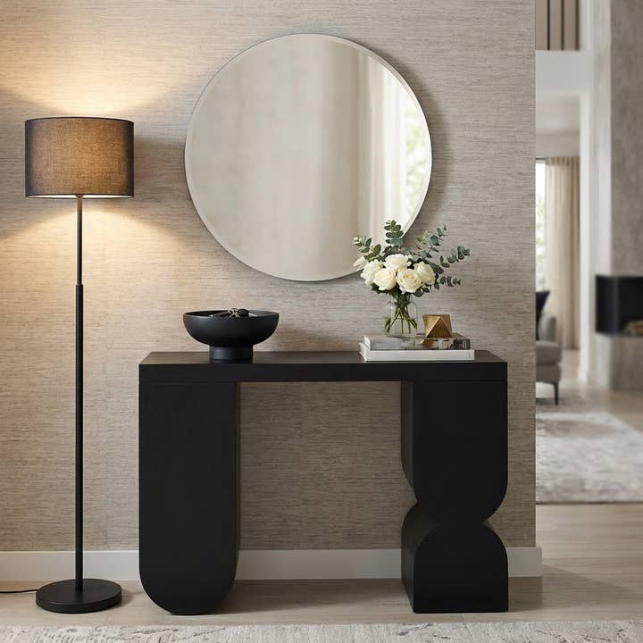 Black mango wood console table with a modern sculptural base on a white background