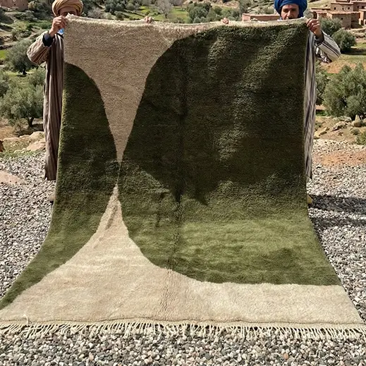 Olive and beige hand-knotted Moroccan rug held up outdoors